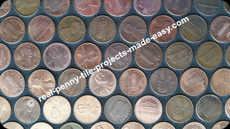 Close-up on black-grouted pennies installed as tile sheets on floor.