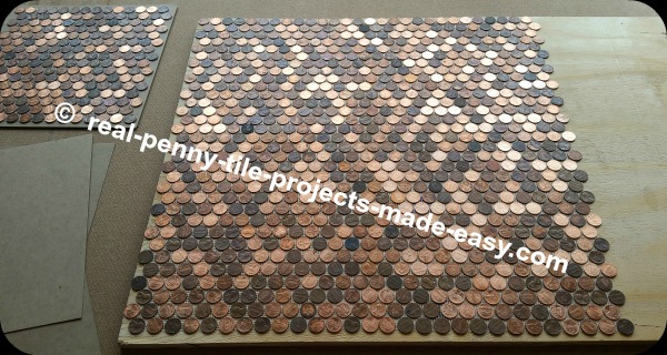 Four sheets of pennies placed down on plywood.
