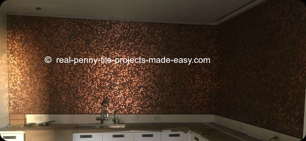 Backsplash made with random pennies on our standard real penny tile. Wall covered in sheets of pennies from countertop to ceiling.
